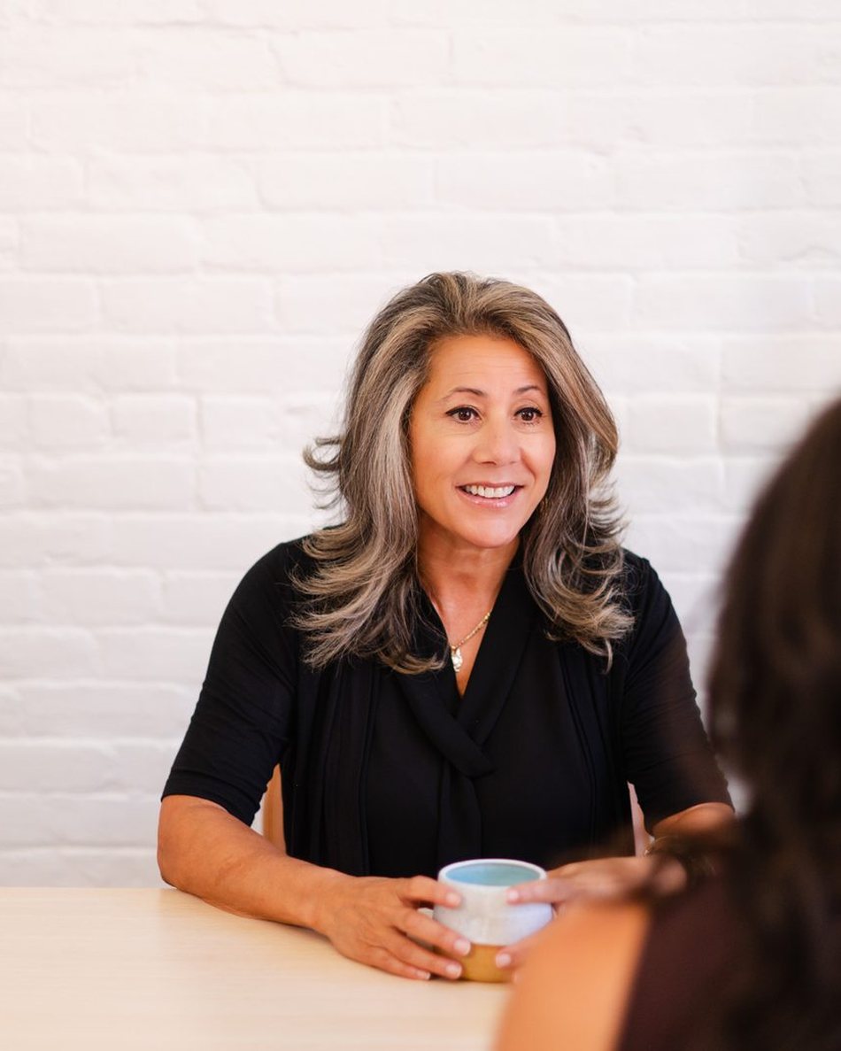 Monique Alem&aacute;n in conversation across a table