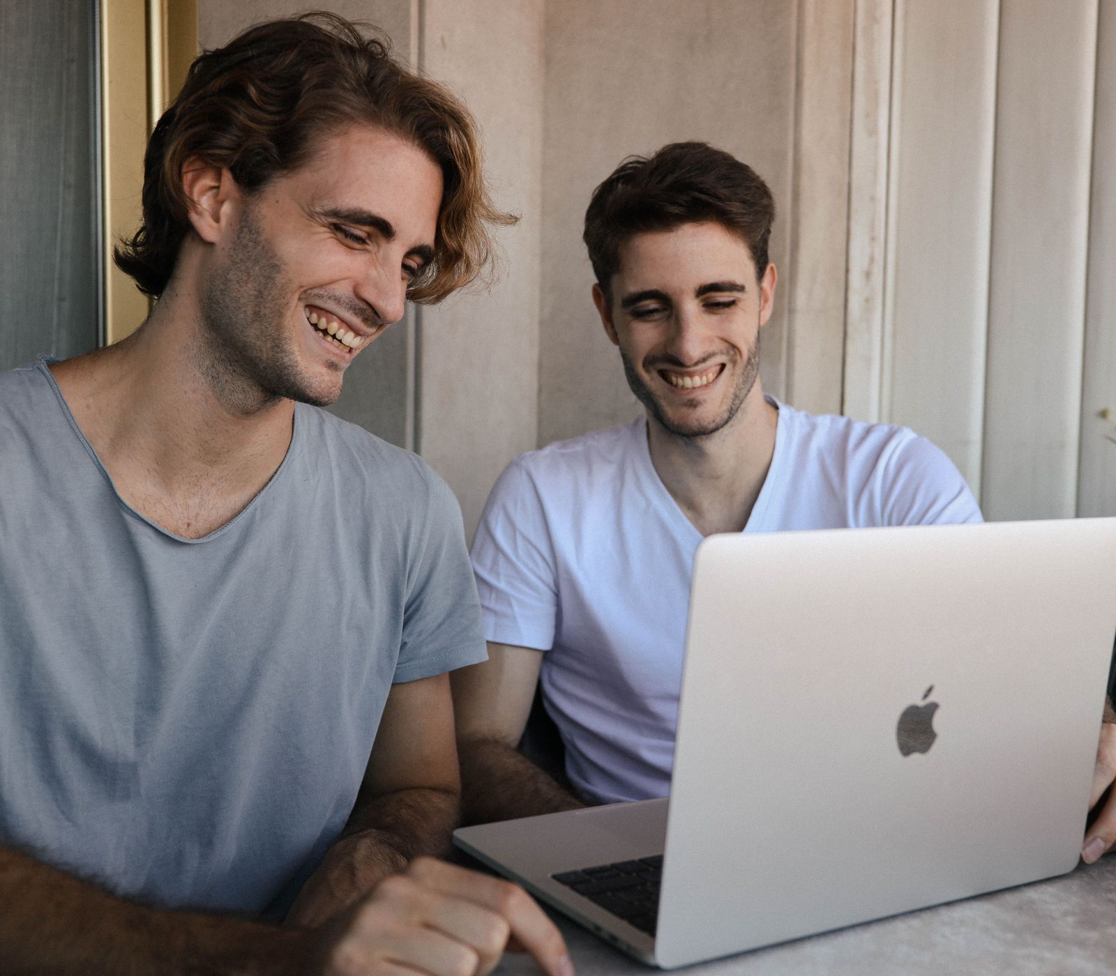 Two adult sons at a laptop, looking through The Garden for their parent